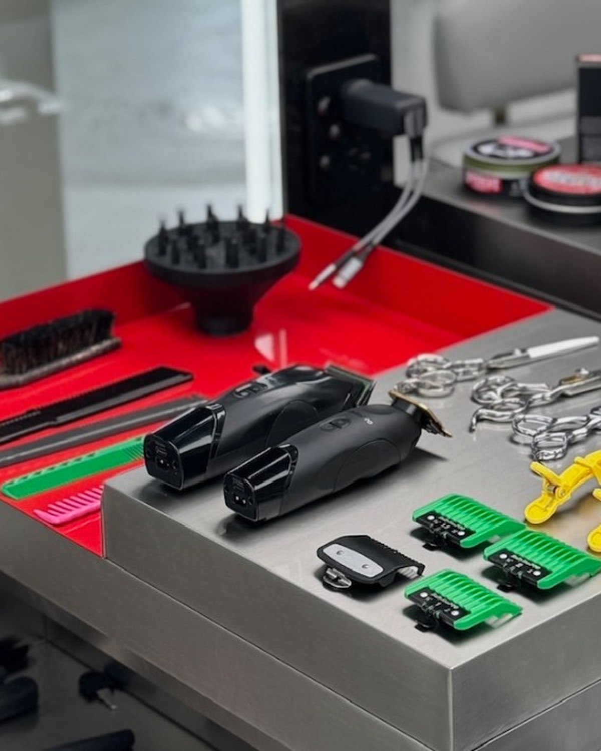 Barber clippers, shears, and guards laid out on a steel station